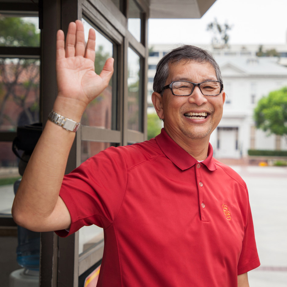 USC entry guard wearing red SC monogram shirt, smiling and waving at camera